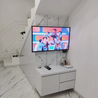 Backdrop TV marmer putih dengan kabinet melayang di samping lemari bawah tangga
