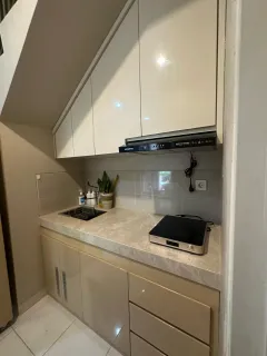 Kitchen set krem di bawah tangga dengan kabinet atas mengikuti kemiringan tangga