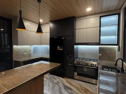 Island dapur dengan top table cokelat dan kabinet hitam di belakangnya