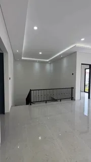 Area lantai atas dengan railing tangga hitam dan plafon bertingkat