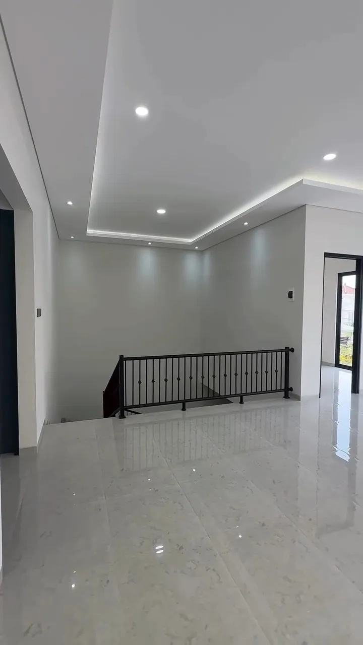 Area lantai atas dengan railing tangga hitam dan plafon bertingkat