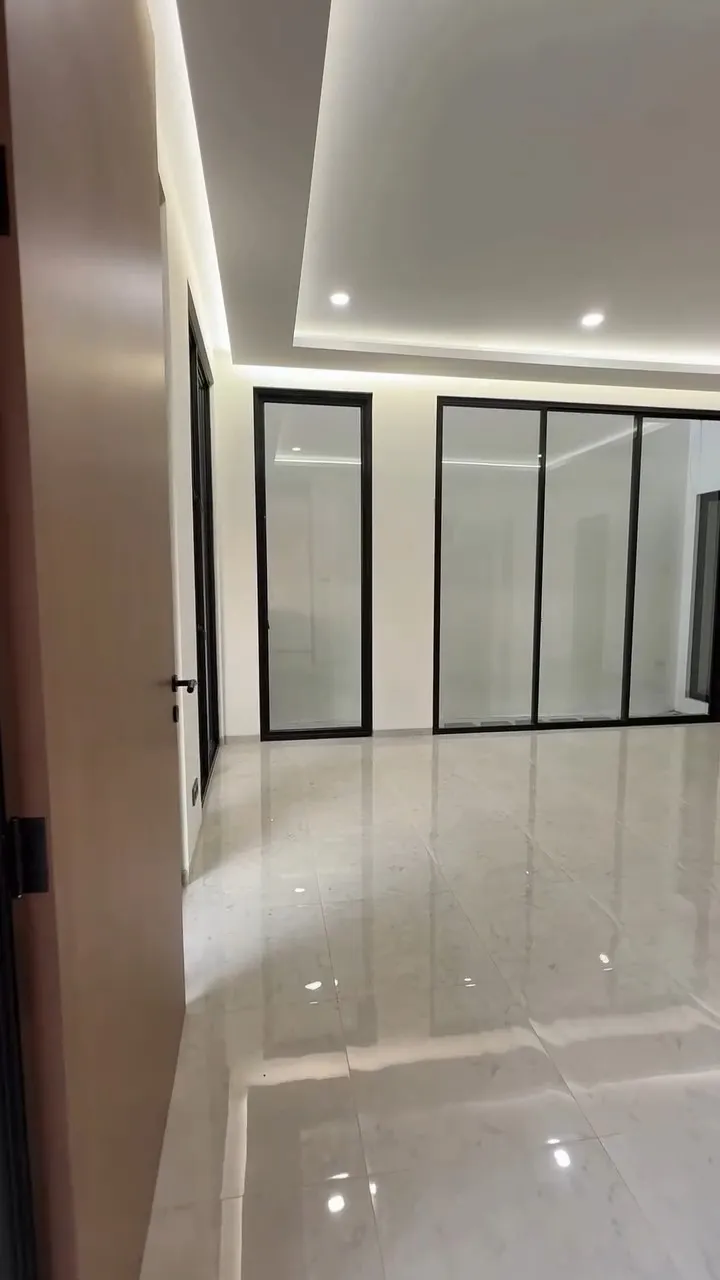 Ruang dalam rumah dengan plafon berlampu tersembunyi dan deretan jendela kaca besar