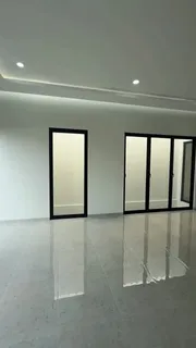 Ruang keluarga kosong dengan lantai granit mengilap dan pintu kaca berkusen hitam