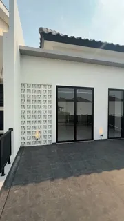 Teras lantai atas rumah di Jakarta dengan dinding roster putih dan pintu kaca berkusen hitam
