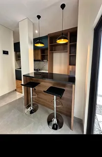 Minibar dengan dua kursi dan lampu gantung di ujung dapur