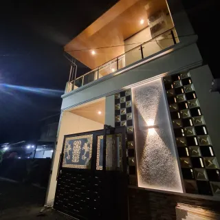 Rumah dua lantai di Tangerang pada malam hari dengan lampu fasad dan plafon kayu di balkon