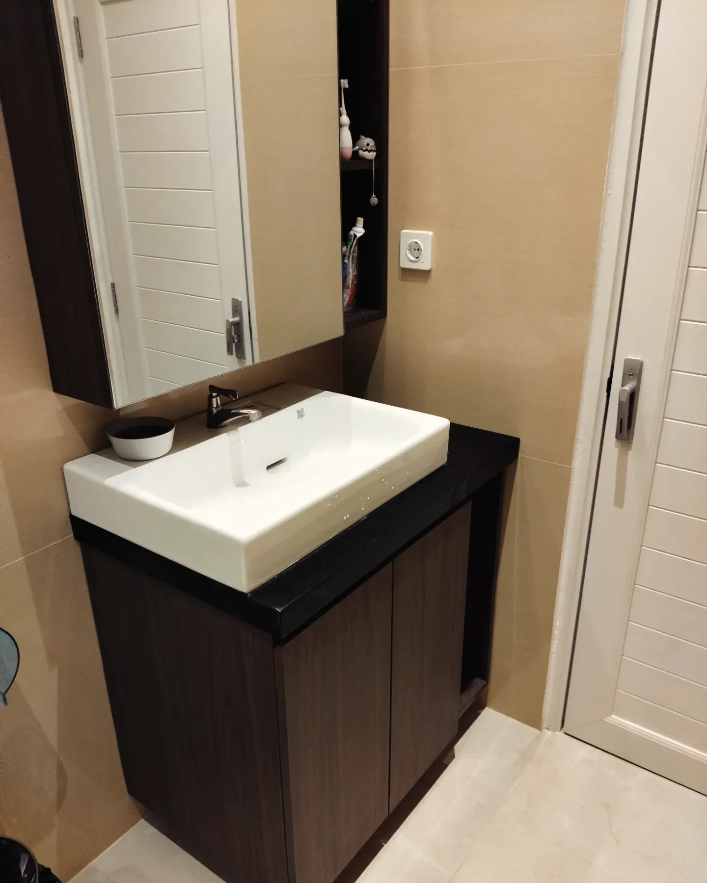 Wastafel putih di atas kabinet gelap dilihat dari dekat