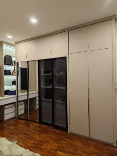 Wardrobe krem sampai plafon dengan pintu kaca gelap dan meja rias berlampu